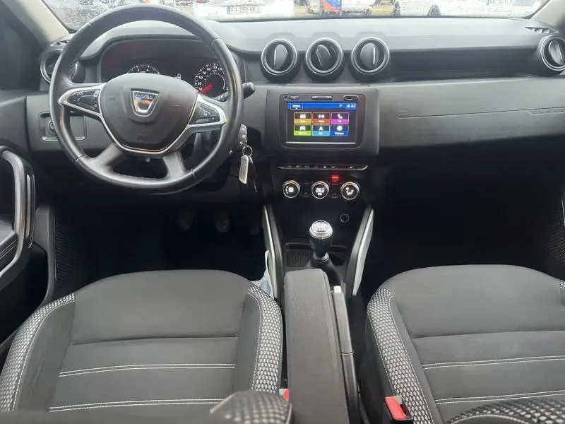 Intérieur du Dacia Duster 2021, vue frontale du tableau de bord avec volant multifonction et écran tactile central.