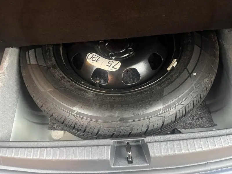 Roue de secours noire avec étiquette de vitesse visible dans le coffre du Dacia Duster 2021 gris Comète métallisé