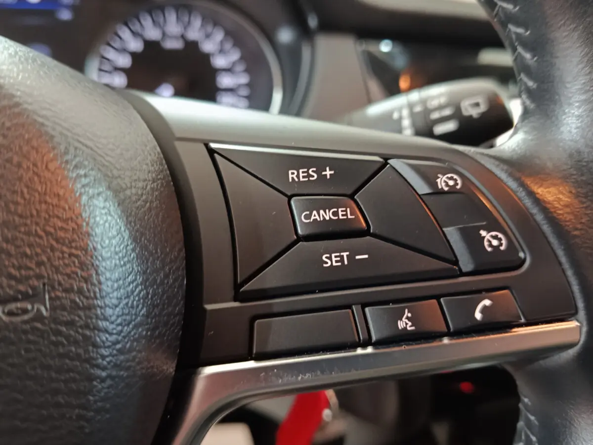 Gros plan sur les commandes de régulateur de vitesse et téléphone au volant cuir du Nissan Qashqai 2019.