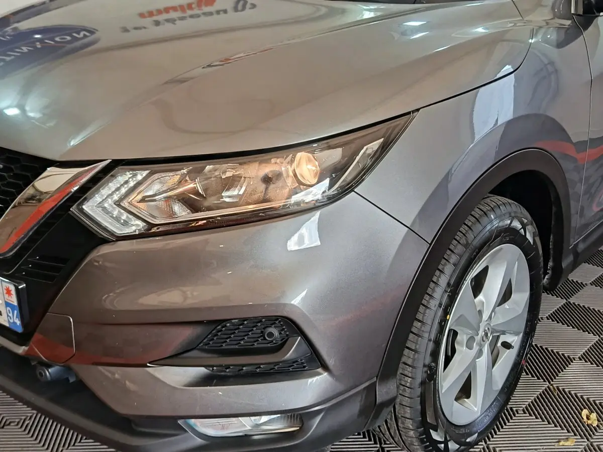 Vue 3/4 avant droit d'un Nissan Qashqai gris clair mettant en valeur le phare avant et la jante alliage.