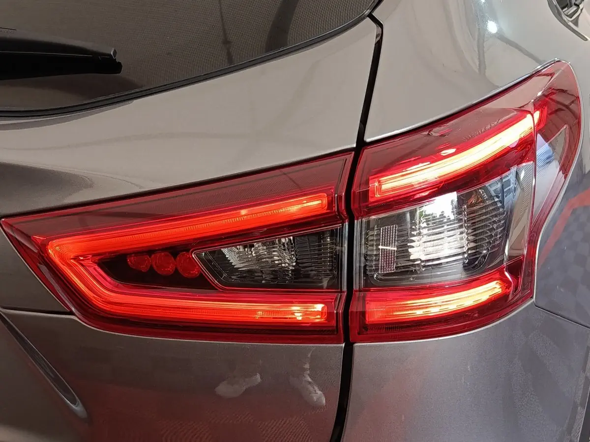 Gros plan sur le feu arrière droit rouge et blanc d’un Nissan Qashqai gris clair, version 2019.