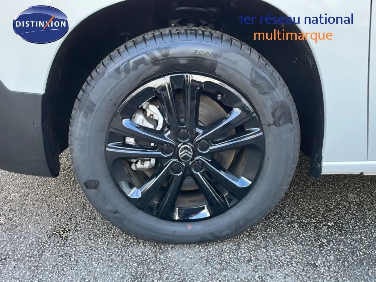 Gros plan sur la roue avant gauche du Citroën Berlingo blanc glacier avec jante noire brillante et logo Citroën central.