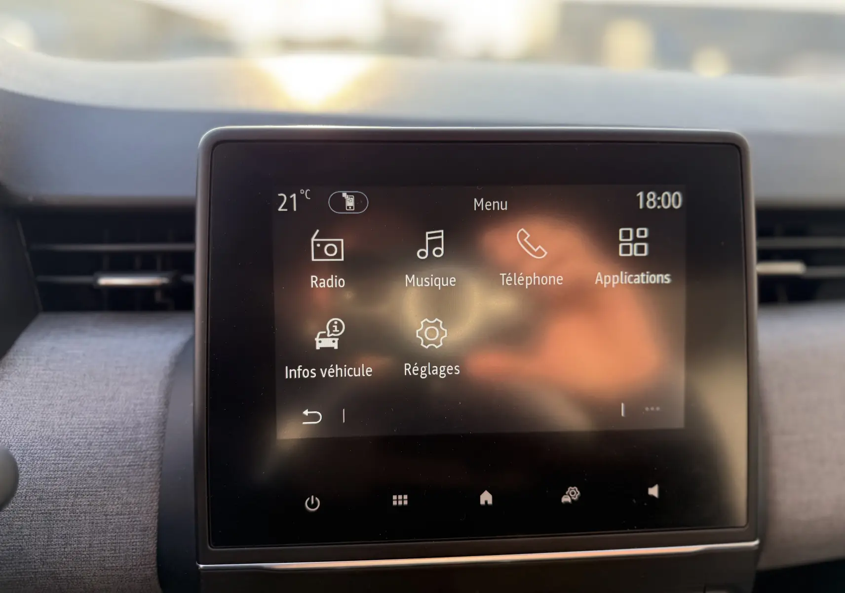 Écran tactile central de la Renault Clio V gris schiste, affichant le menu principal avec options radio, musique et téléphone.