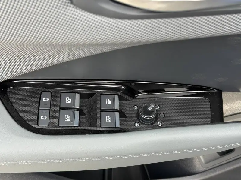 Gros plan sur la commande des vitres et rétroviseurs côté conducteur de l'Audi Q3 2026, finition S line avec surpiqûres grises.