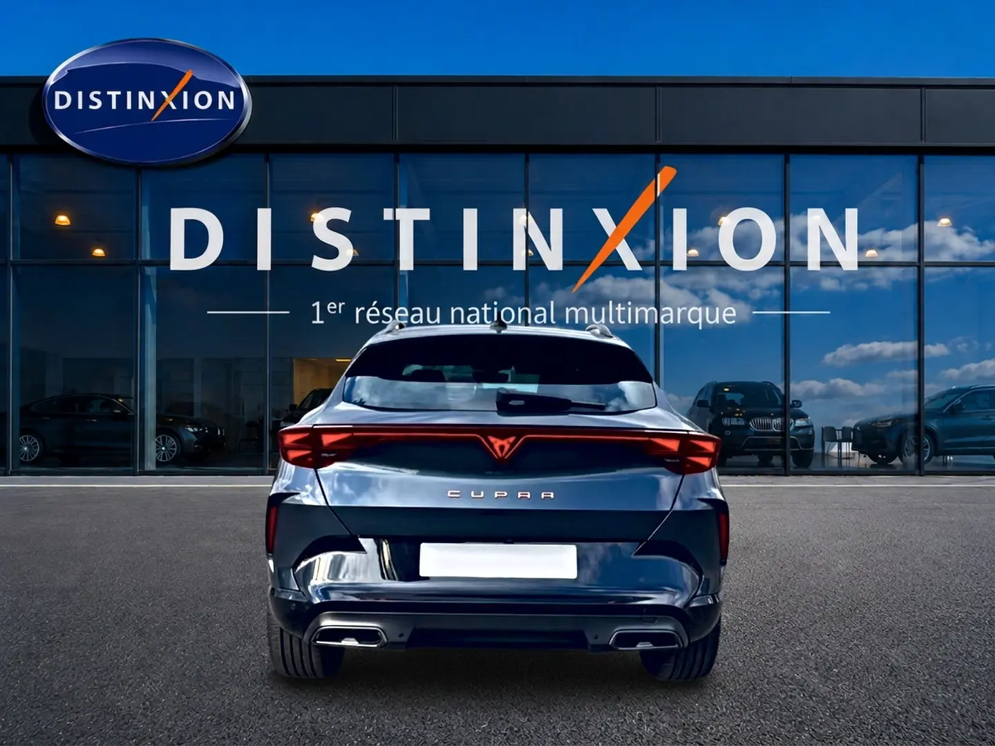 Vue arrière d'une CUPRA Formentor gris magnétique 2026 avec feux LED et double sortie d'échappement, devant une vitrine Distinxion.