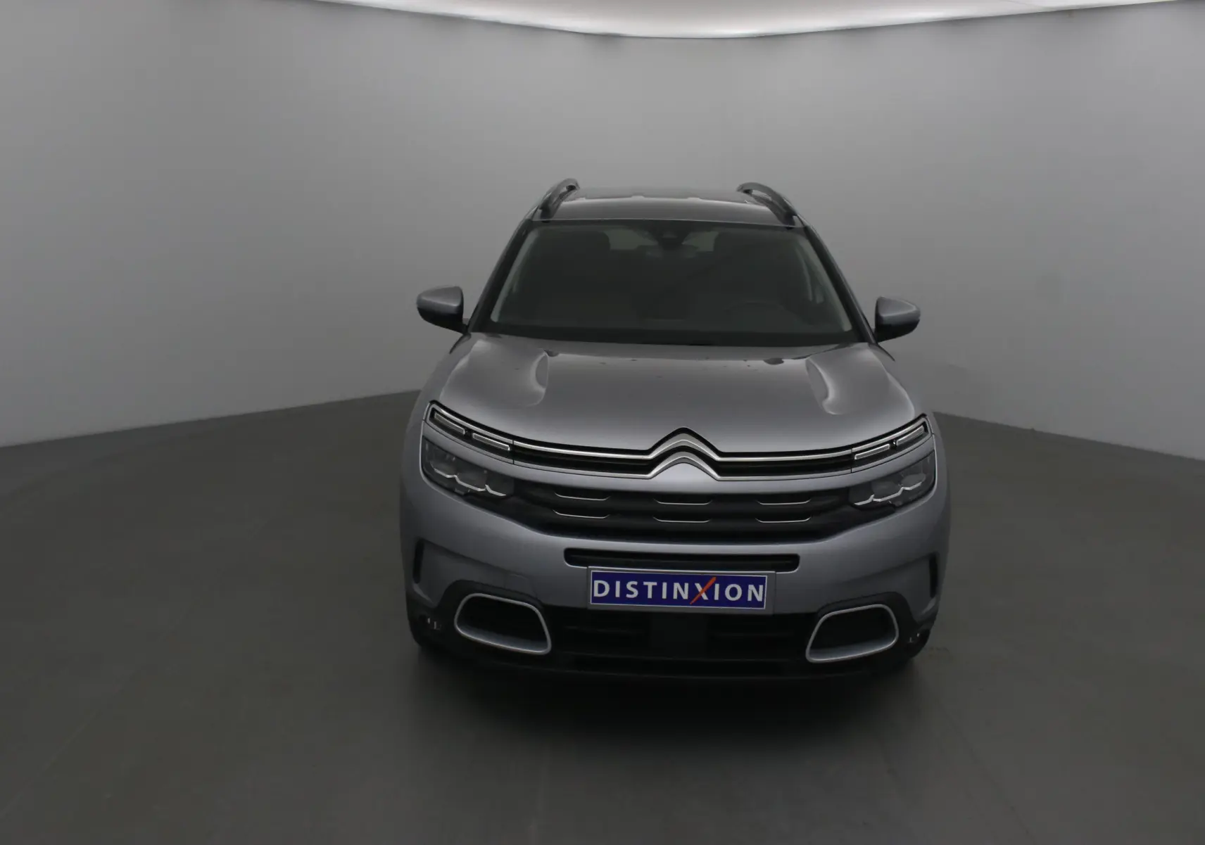 Vue frontale d'un Citroën C5 Aircross gris Artense avec calandre distinctive et plaque Distinxion visible.