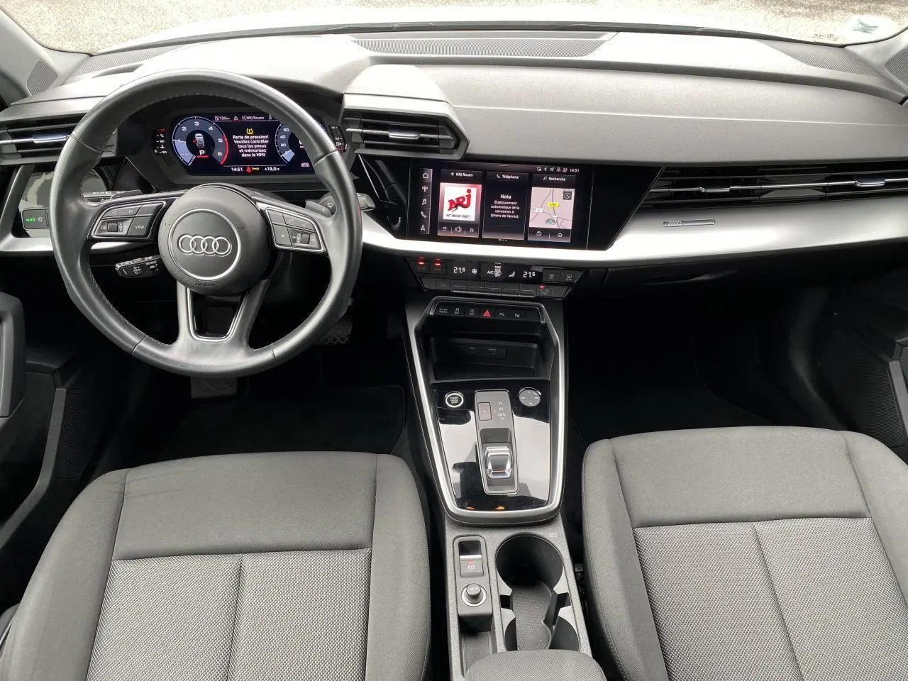 Vue intérieure de l'Audi A3 Sportback 2021 montrant le tableau de bord moderne avec écran tactile et volant cuir multifonctions.