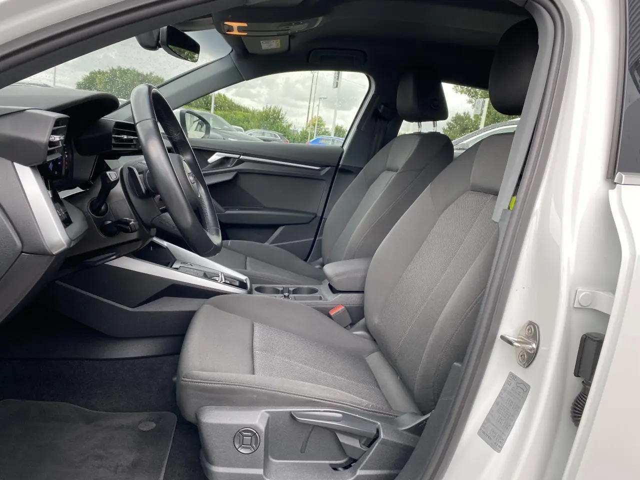 Intérieur côté conducteur Audi A3 Sportback blanc Ibis 2021, sièges tissu gris et volant cuir multifonctions.