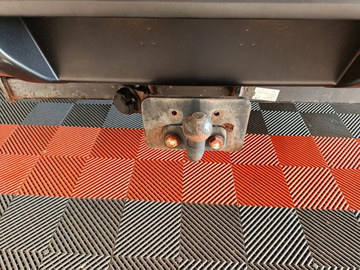 Gros plan sur l'attelage rouillé du Nissan Navara gris clair, vue centrée sous l'arrière du véhicule.