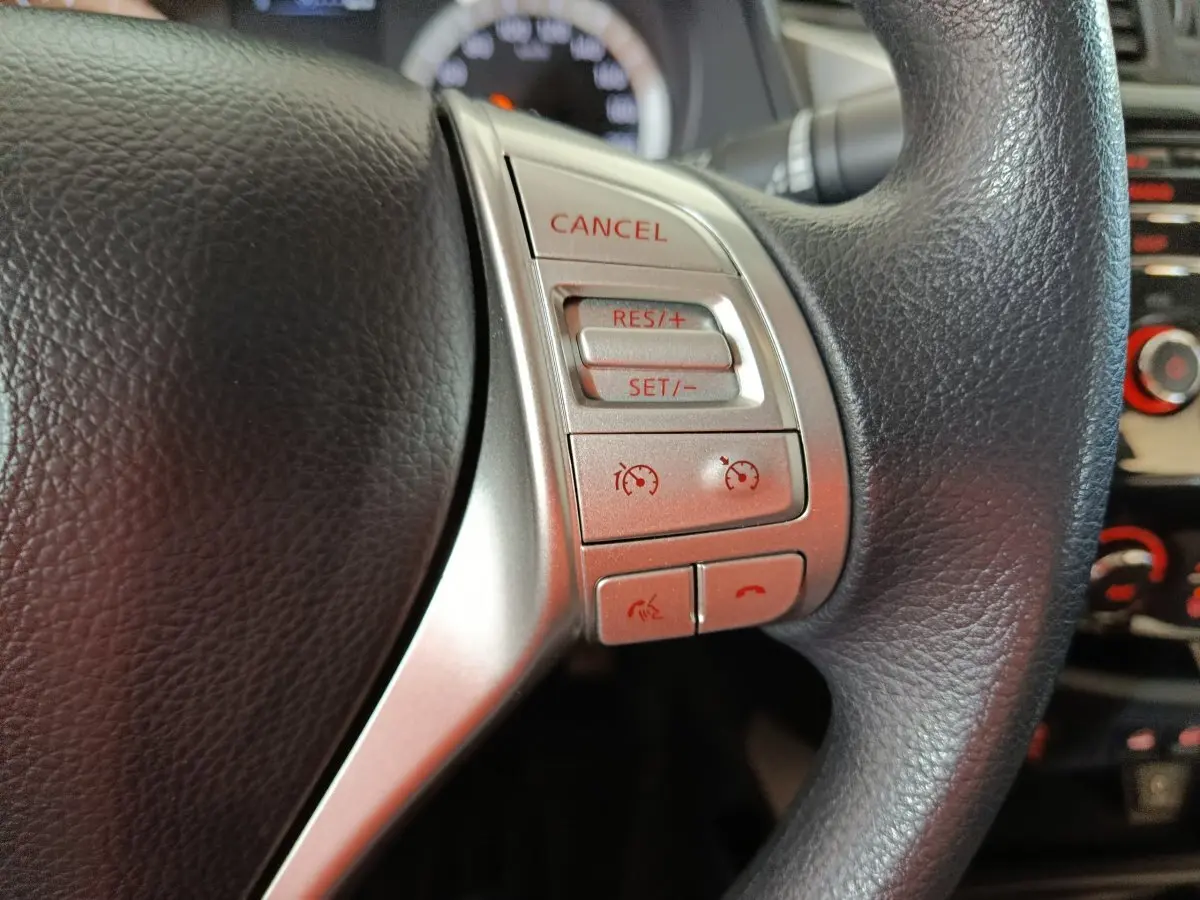 Gros plan sur les commandes multifonctions argentées du volant noir du Nissan Navara gris clair, version Acenta 2018.