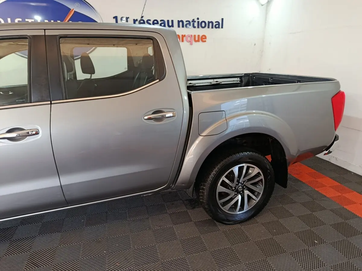 Vue latérale droite du Nissan Navara Double-Cab gris clair, mettant en valeur la benne pick-up et la roue arrière avec jante alliage.