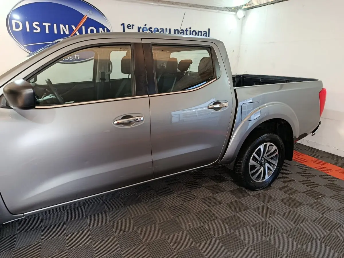 Vue latérale côté gauche d'un Nissan Navara Double-Cab gris clair avec benne pick-up et jantes alliage.