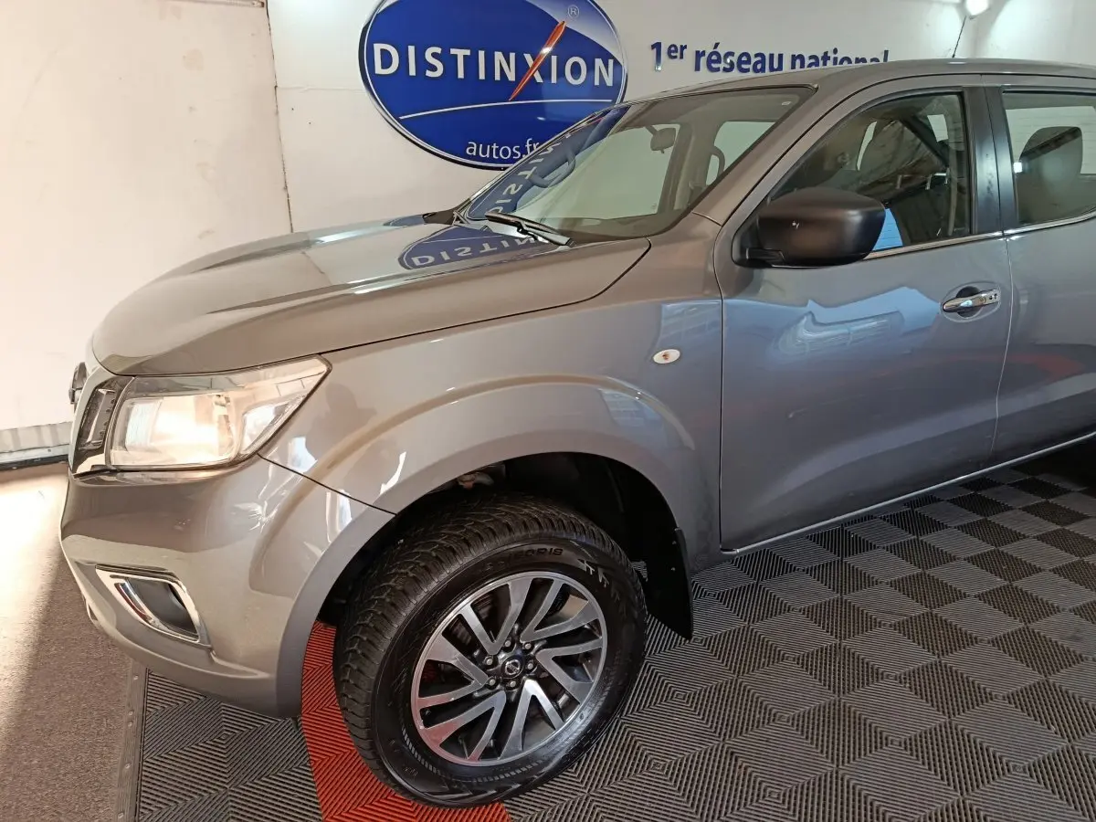 Vue 3/4 avant droit du Nissan Navara gris clair Double-Cab 2018 avec jantes alliage et rétroviseur noir.