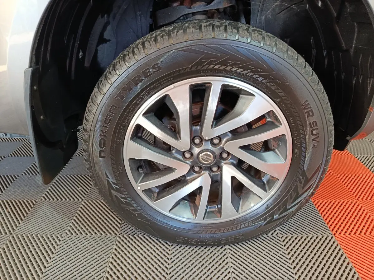 Gros plan sur la roue avant droite du Nissan Navara gris clair, jante alliage et pneu Nokian Tyres visible.