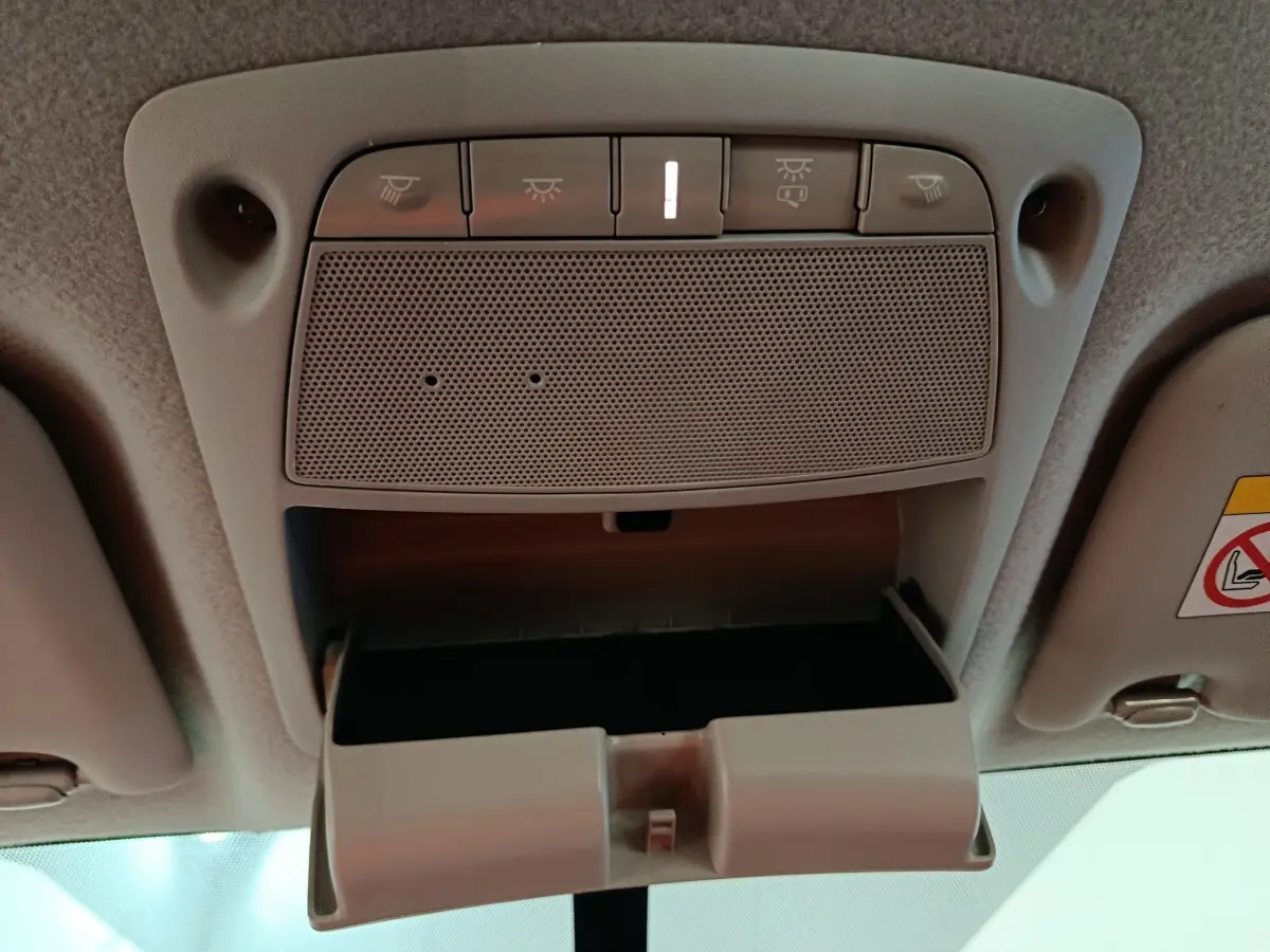 Vue intérieure en plongée du compartiment lunettes ouvert et des commandes d'éclairage au plafond du Nissan Navara gris clair.