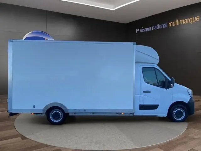 Vue de profil droit d’un Renault Master blanc 2022 avec caisse de grande capacité, en intérieur showroom.