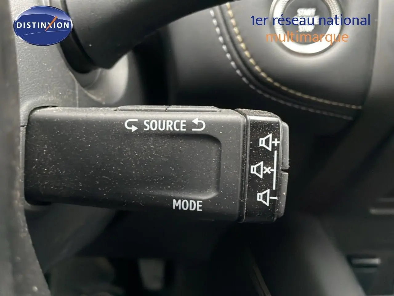 Gros plan sur la commande au volant noir étoile métal de la Renault Symbioz 2025, avec boutons source et mode visibles.