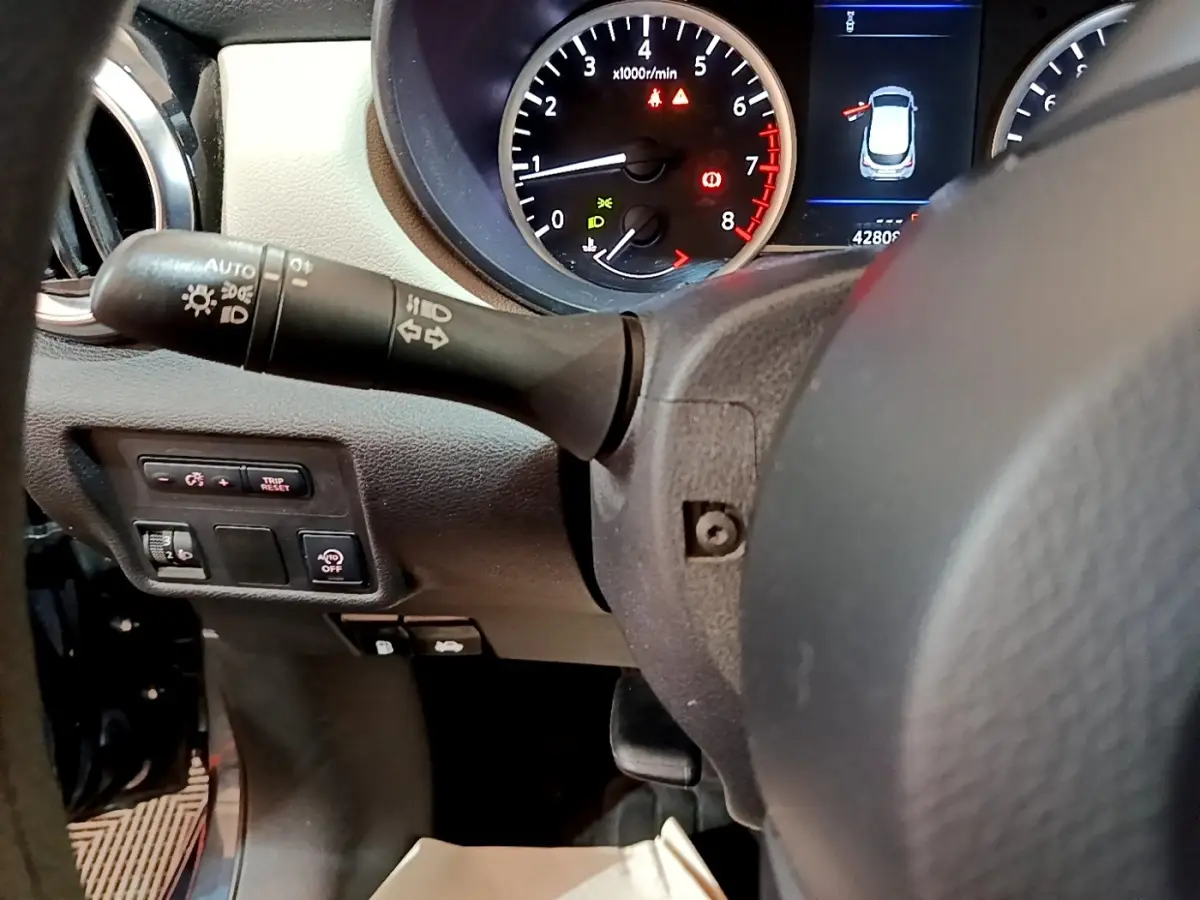 Vue rapprochée du tableau de bord et du volant de la Nissan Micra gris foncé, avec compte-tours et commandes lumineuses visibles.