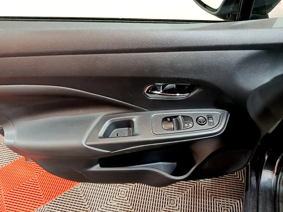 Vue rapprochée de la porte avant gauche gris foncé de la Nissan Micra avec commandes électriques des vitres et rétroviseurs.