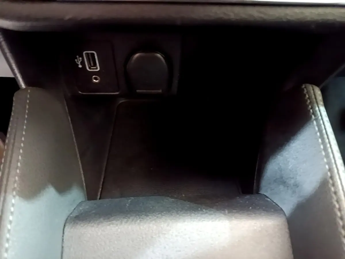 Gros plan intérieur sur la console centrale noire de la Nissan Micra IG-T 100 Business Edition avec prise USB et prise 12V.