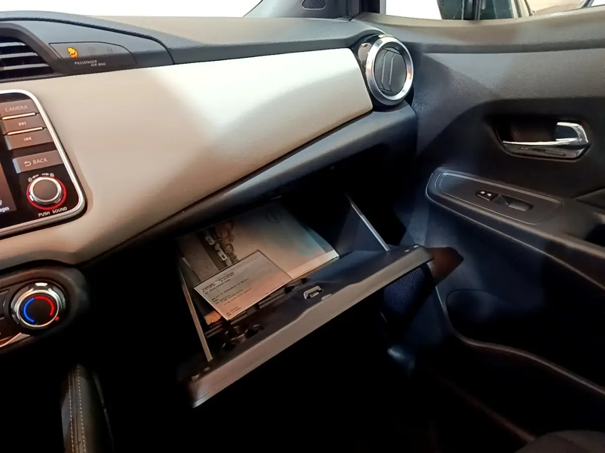 Intérieur côté passager de la Nissan Micra IG-T 100 Business Edition 2020, boîte à gants ouverte et tableau de bord gris clair.