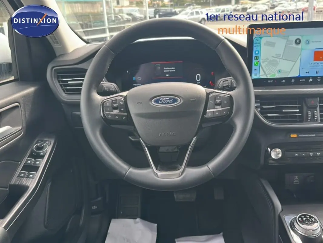 Vue intérieure centrée sur le volant noir du Ford Kuga 2025 avec écran tactile et commandes au volant visibles.