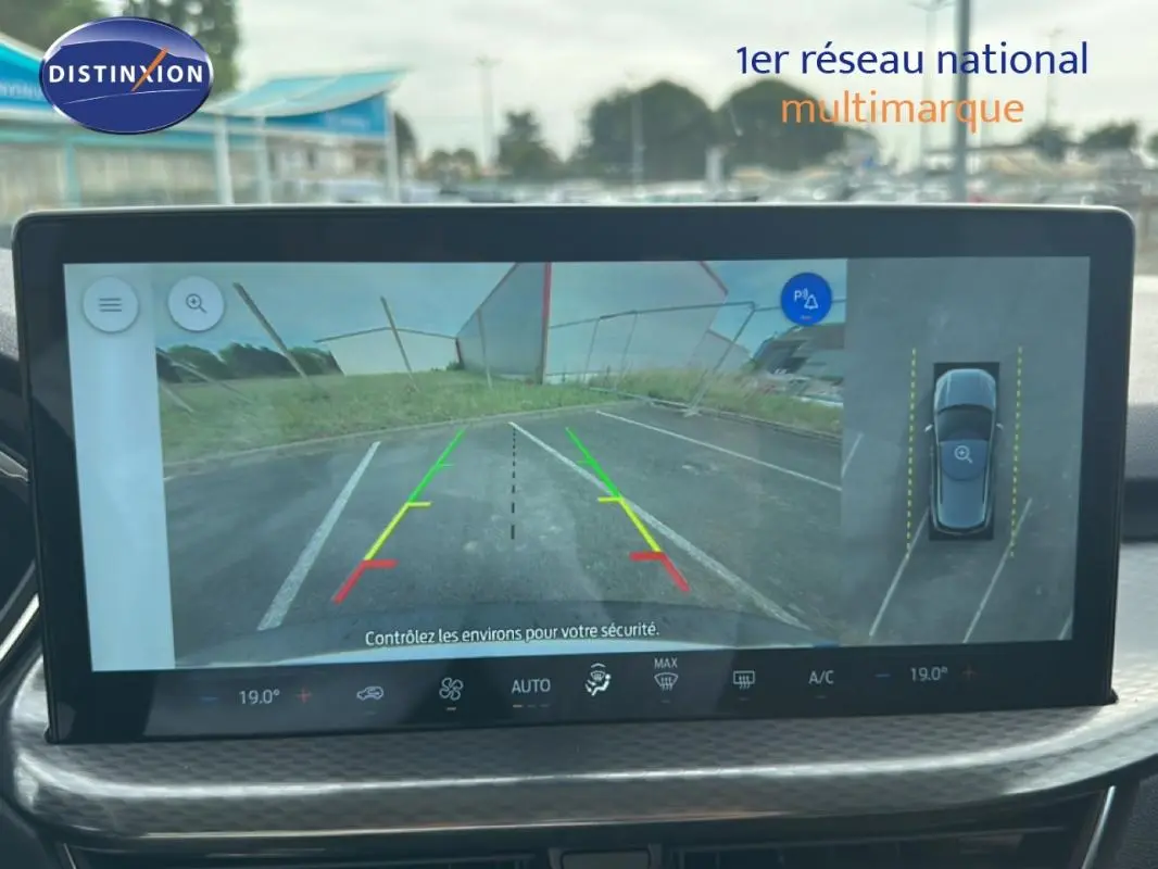 Écran central montrant la caméra de recul du Ford Kuga blanc, avec lignes de guidage colorées et vue 360° du véhicule.