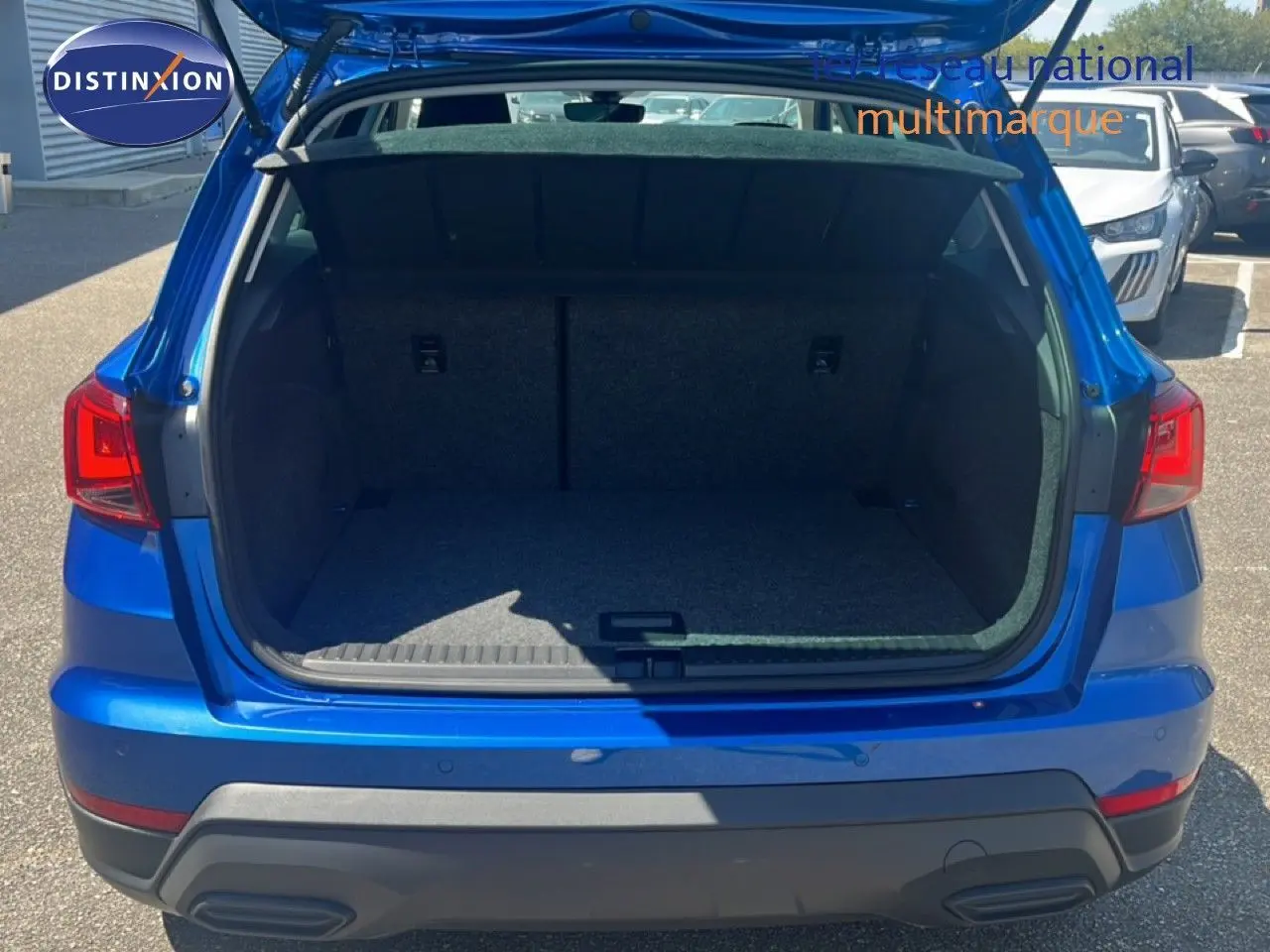 Vue arrière du coffre ouvert d'un SEAT Arona bleu saphir métal avec toit noir, montrant l'espace de chargement vide.