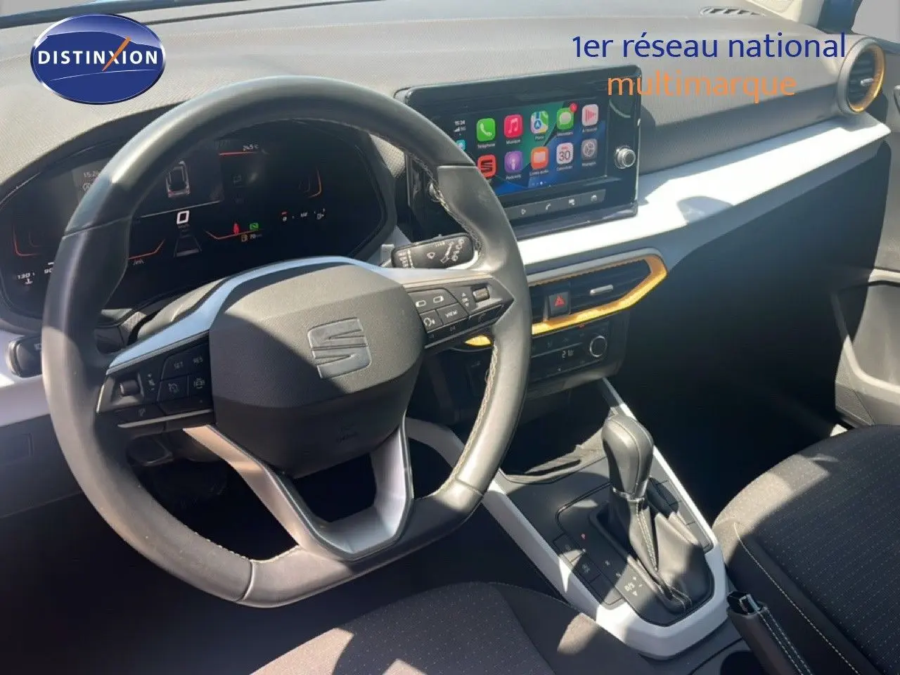 Vue intérieure du poste de conduite du SEAT Arona 2025, volant cuir, écran tactile et levier de boîte automatique.