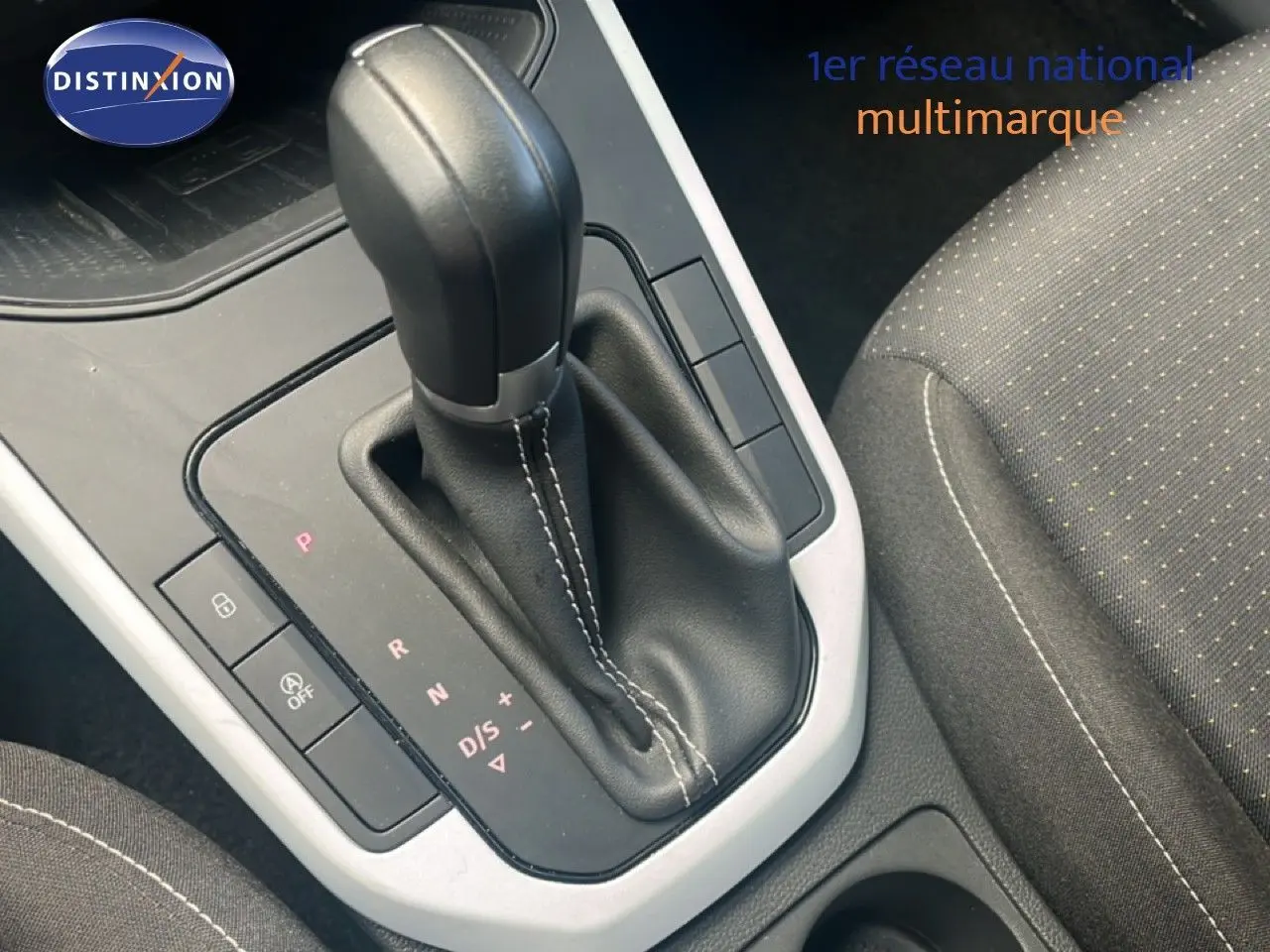 Gros plan sur la console centrale et levier de vitesse automatique du SEAT Arona 2025, intérieur tissu gris.
