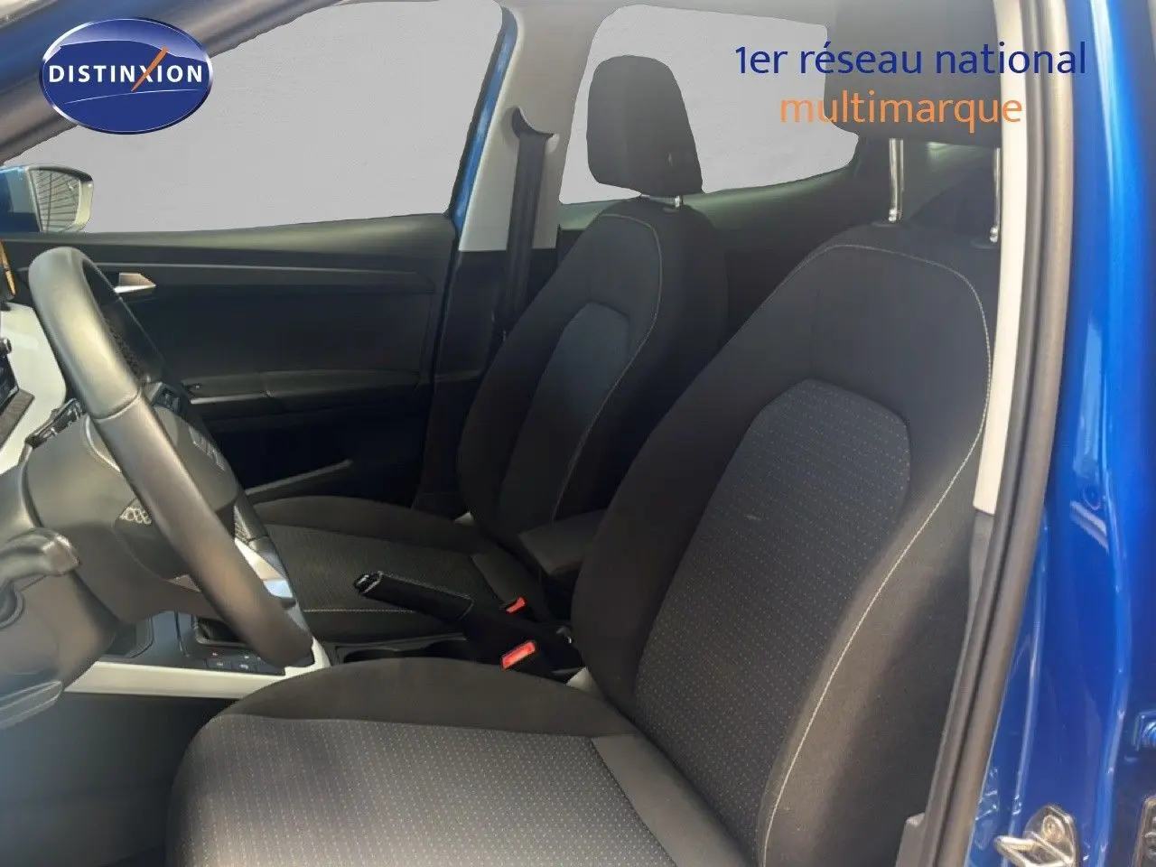 Vue intérieure côté conducteur du SEAT Arona bleu saphir avec sièges en tissu noir et volant cuir.