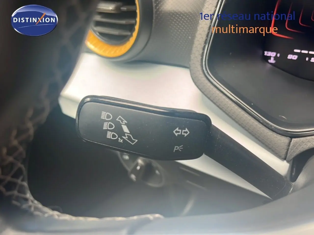 Gros plan sur la commande des clignotants et feux, côté gauche du volant du SEAT Arona bleu saphir 2025.