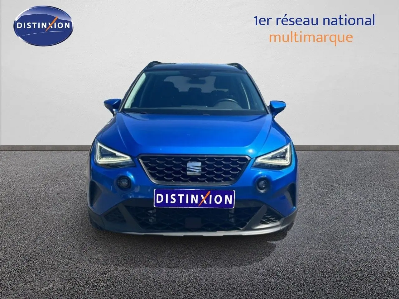 Vue avant d'un SEAT Arona bleu saphir métallisé avec calandre noire et toit noir visible en arrière-plan.