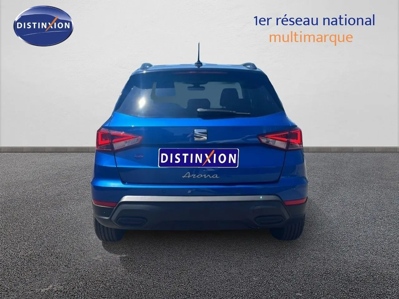Vue arrière d'une SEAT Arona bleu saphir métal avec toit noir, montrant ses feux arrière et son logo central.