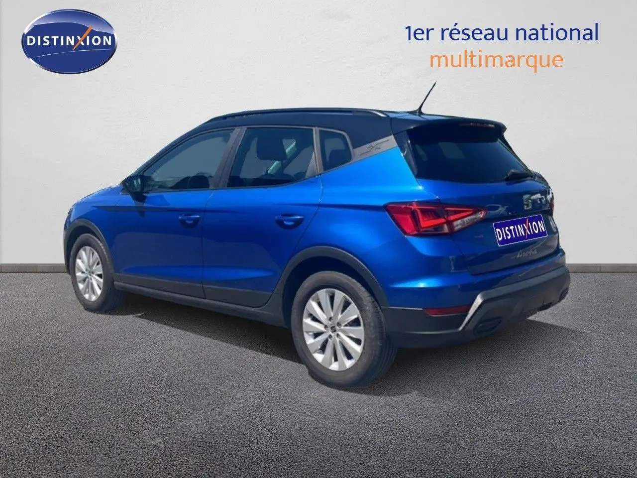 Vue 3/4 arrière droite d’un SEAT Arona bleu saphir avec toit noir, sur fond neutre extérieur.