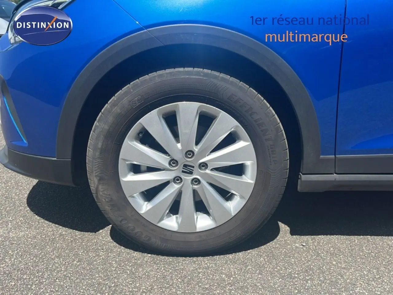 Gros plan sur la roue avant gauche d’un SEAT Arona bleu saphir avec jante alu et entourage noir.