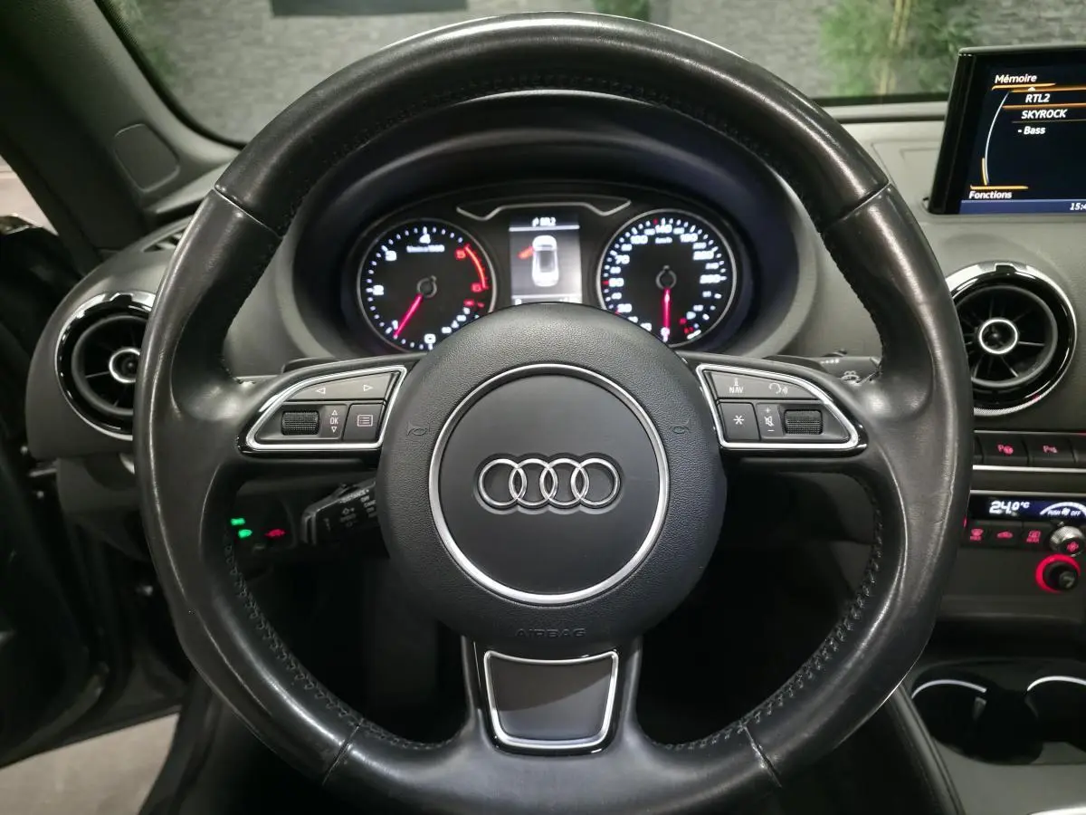 Vue rapprochée du volant cuir noir multifonction et du tableau de bord d'une Audi A3 Cabriolet gris foncé de 2015.