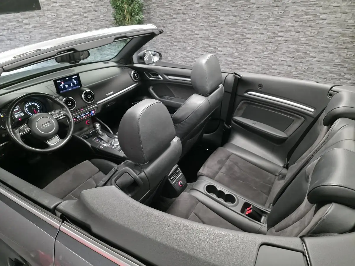 Vue intérieure de l'Audi A3 Cabriolet gris foncé, montrant les sièges en alcantara/cuir et le tableau de bord moderne.