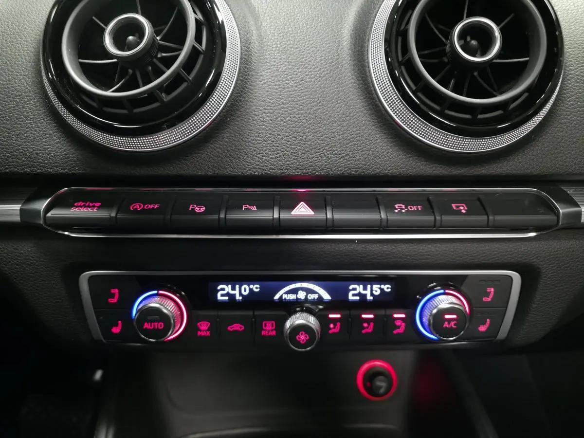 Détail du tableau de bord noir de l'Audi A3 Cabriolet 2015 avec commandes de climatisation automatique et aérateurs ronds chrome.