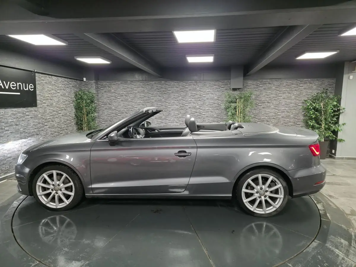 Profil droit d'un cabriolet Audi A3 gris foncé avec capote ouverte et jantes sport 10 branches en aluminium.