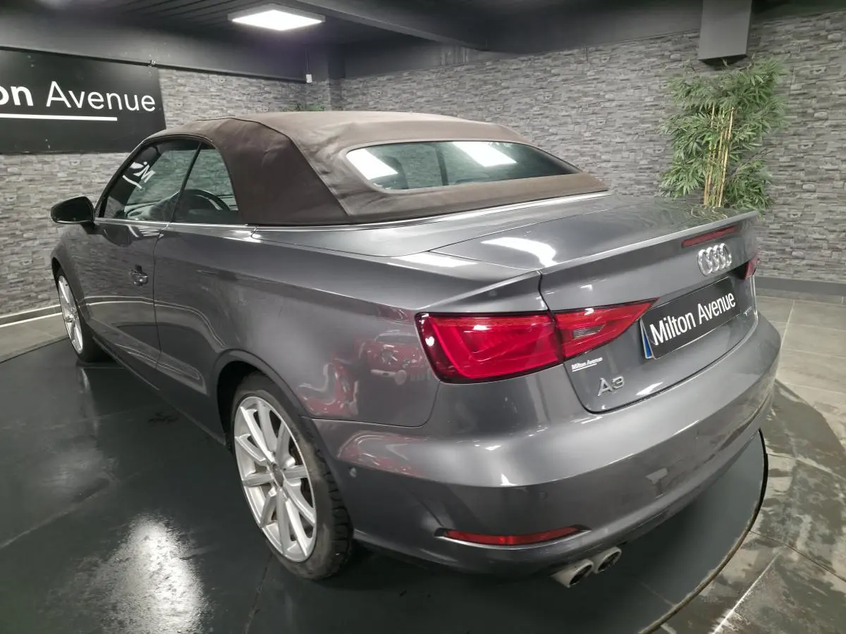 Audi A3 Cabriolet gris foncé vue 3/4 arrière droit avec capote noire et doubles sorties d'échappement chromées.