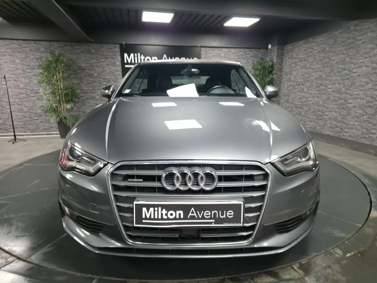 Audi A3 Cabriolet gris foncé vue de face en intérieur avec calandre Singleframe et logo Audi bien visibles.