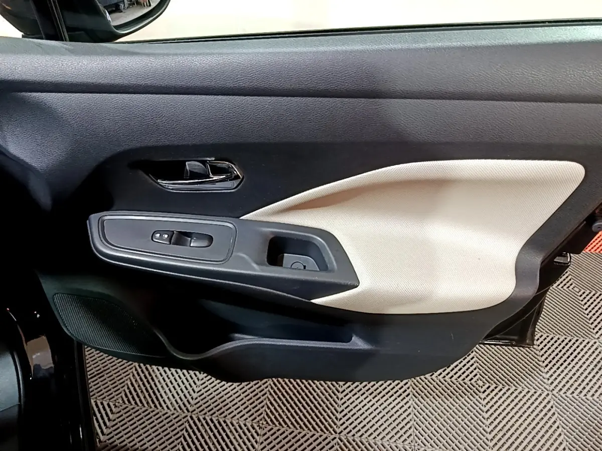 Vue rapprochée de la porte avant gauche de la Nissan Micra noire, avec insert beige et commandes de vitres.