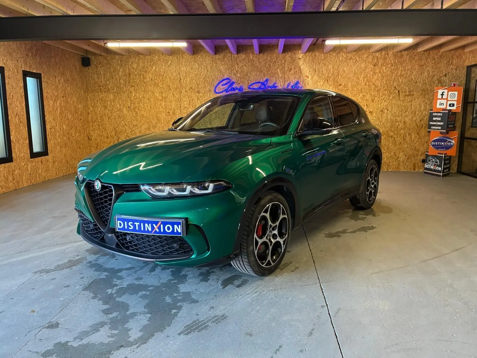 Vue 3/4 avant d'une Alfa Romeo Tonale 1.5 MHEV 130 TCT7 vert foncé avec jantes distinctives en intérieur showroom.