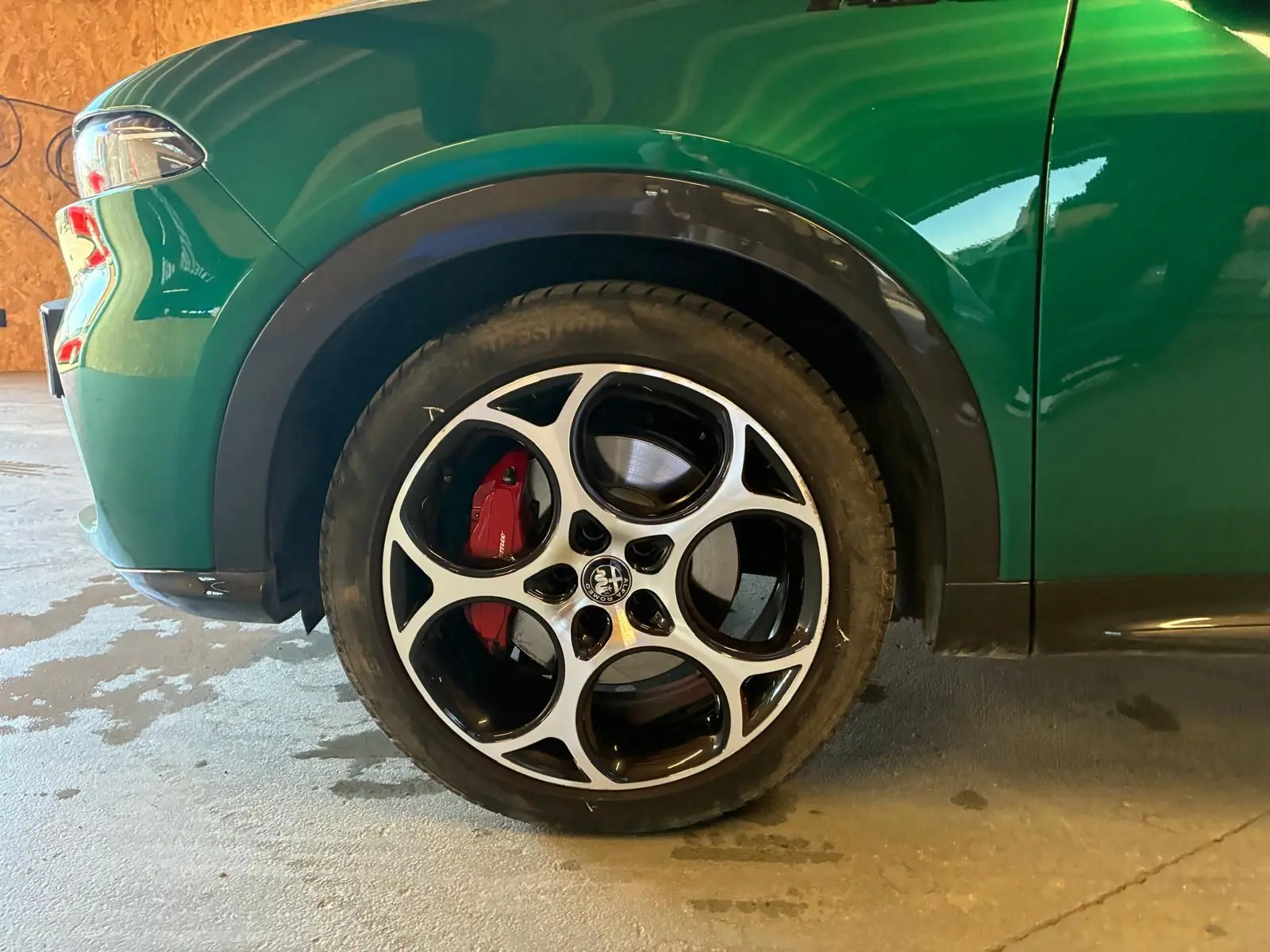 Gros plan sur la roue avant gauche d'une Alfa Romeo Tonale vert foncé avec étrier de frein rouge et jante noire et argent.
