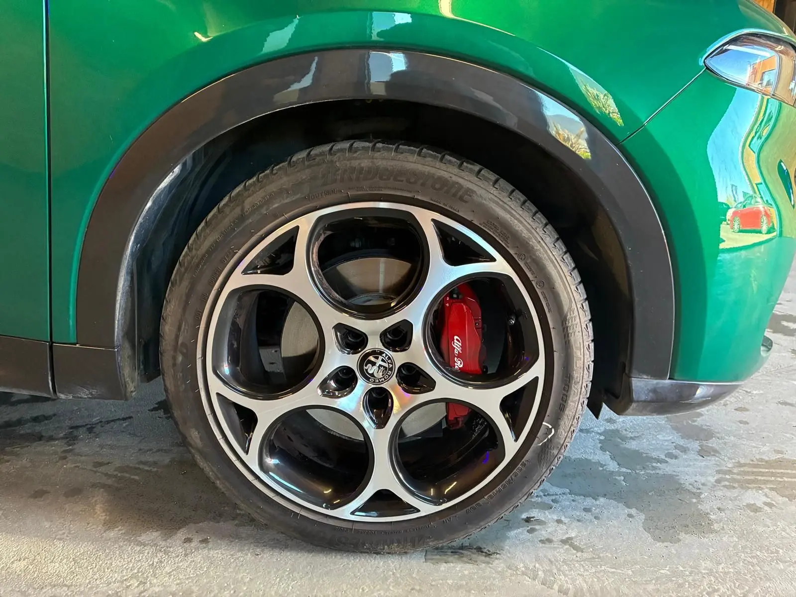 Gros plan sur la roue avant droite d’un Alfa Romeo Tonale vert foncé avec étrier de frein rouge et jante à cinq cercles.
