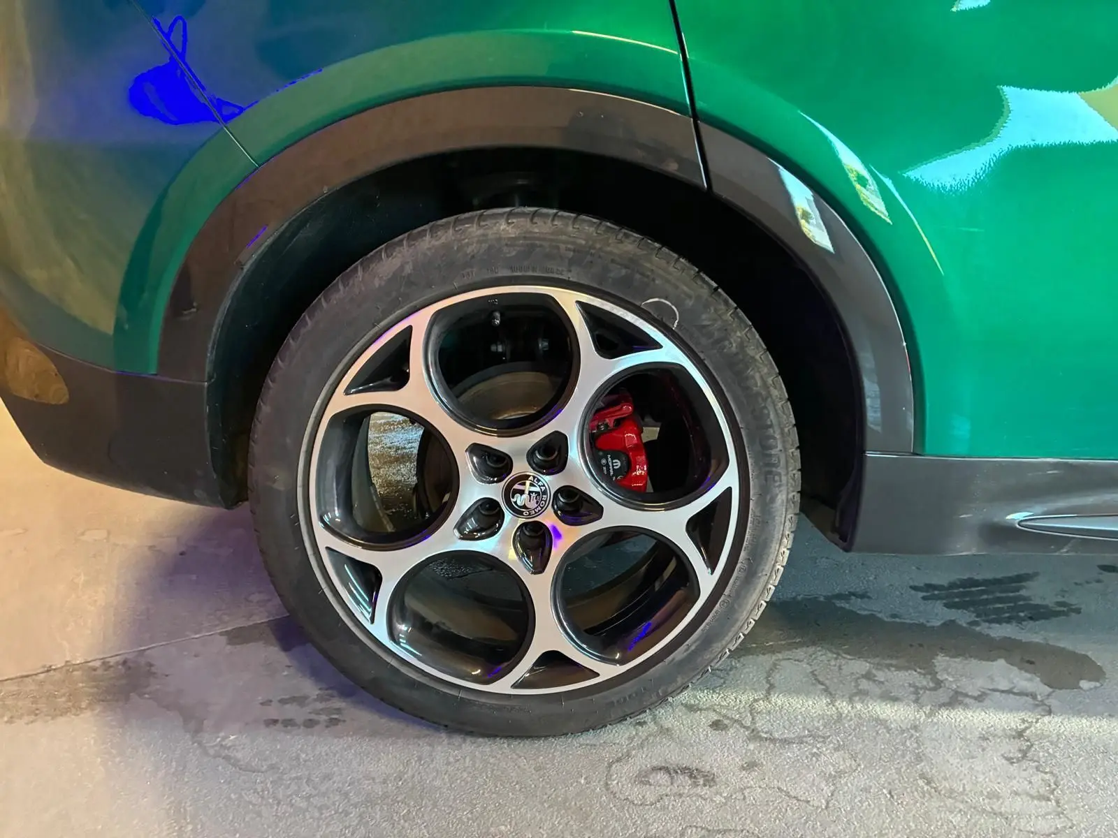 Gros plan sur la roue arrière droite d'une Alfa Romeo Tonale vert foncé, avec étrier de frein rouge visible.