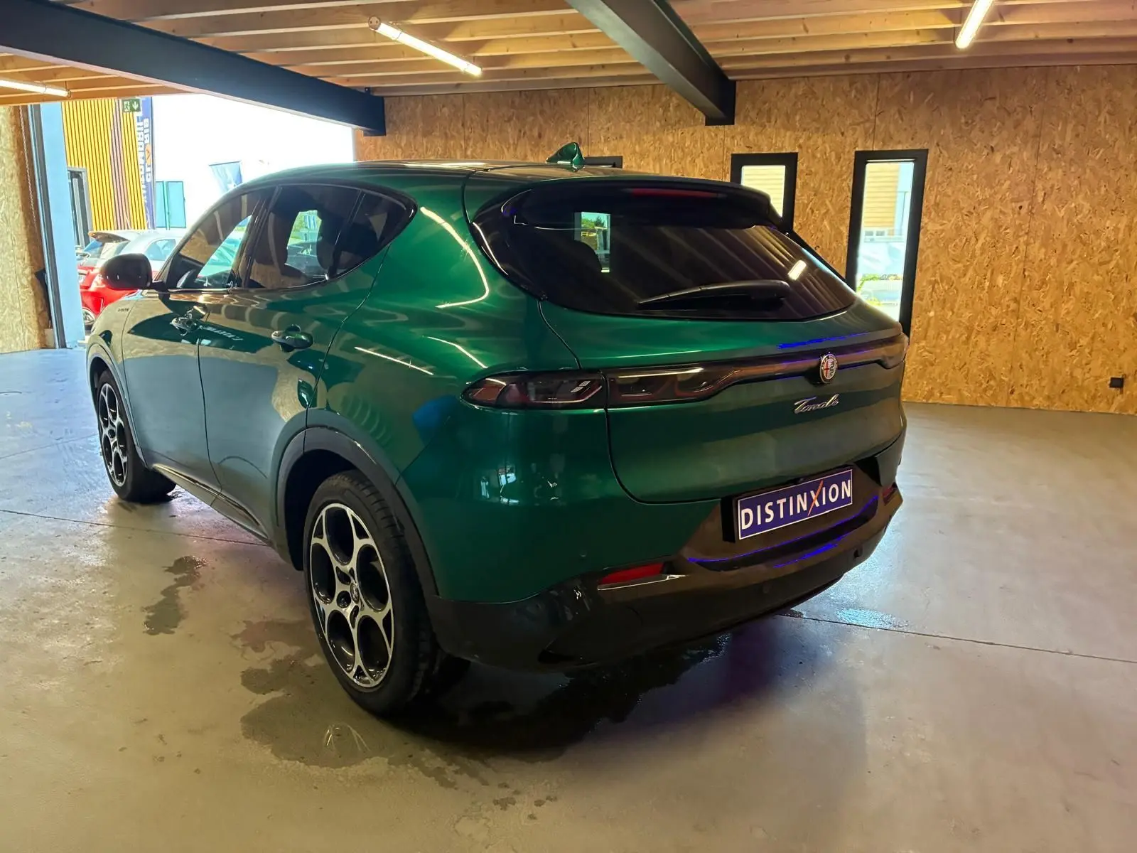 Vue 3/4 arrière droite de l'Alfa Romeo Tonale vert foncé, avec feux arrière fins et jantes distinctives en cercle.
