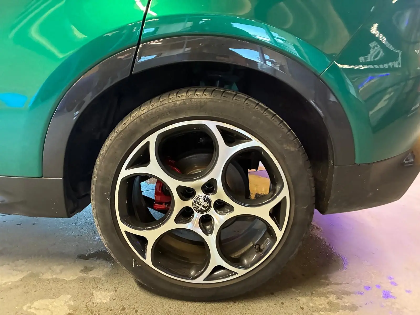 Gros plan sur la roue arrière droite d'une Alfa Romeo Tonale vert foncé avec jante alliage et étrier de frein rouge.