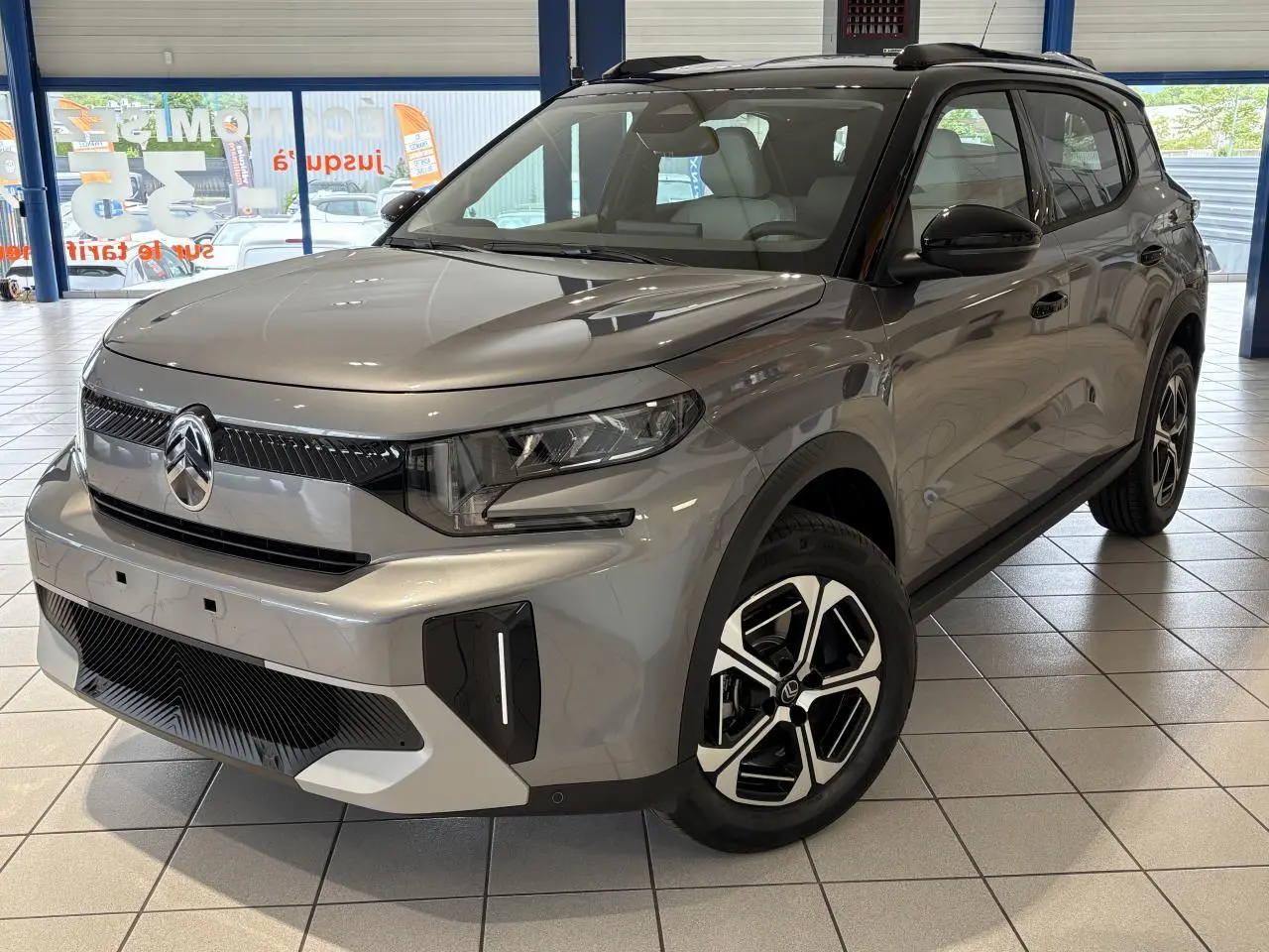 Vue 3/4 avant d'un Citroën C3 Aircross 2026 gris métallisé avec toit noir et jantes alliage 17 pouces.
